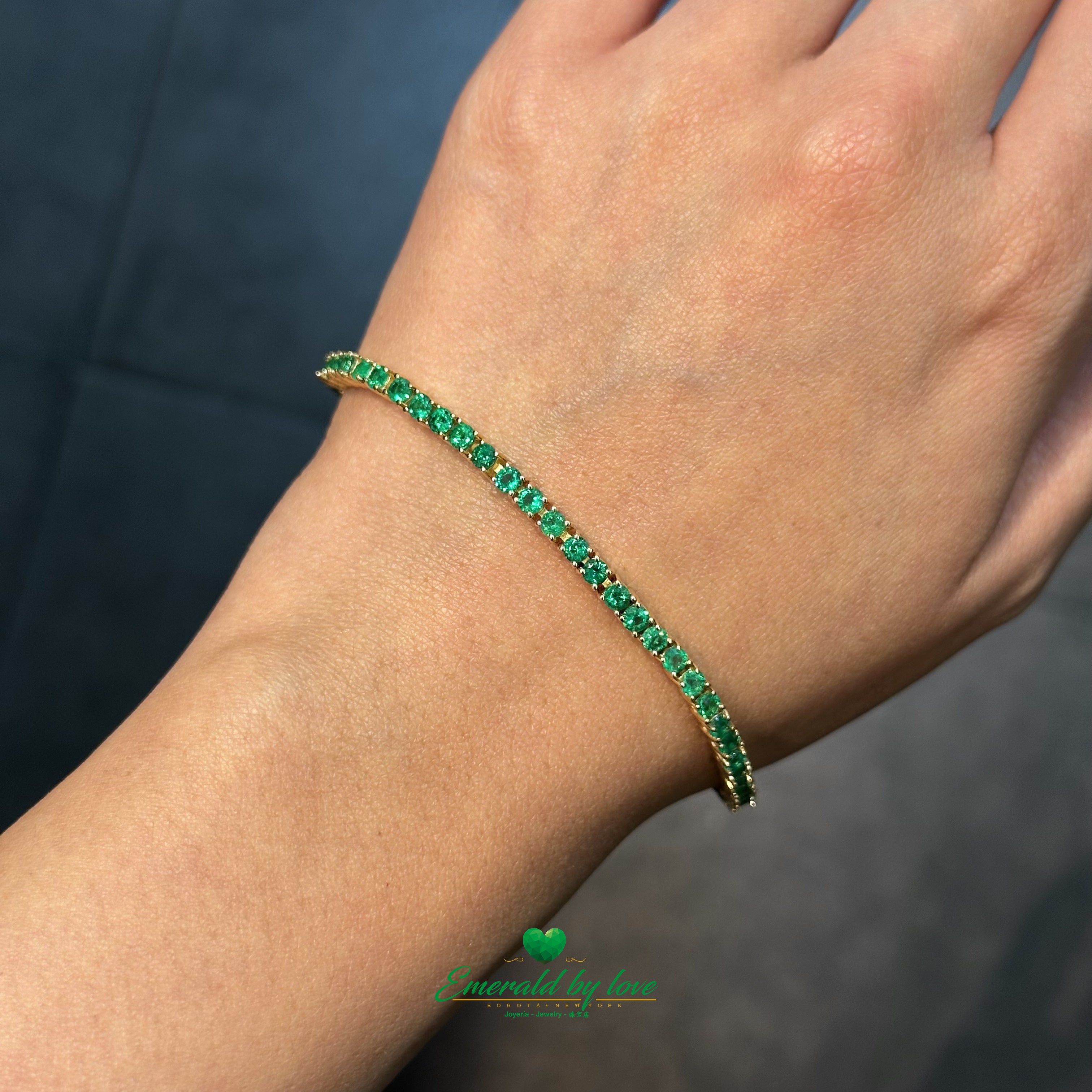 Prong-mounted emerald tennis bracelet on white background