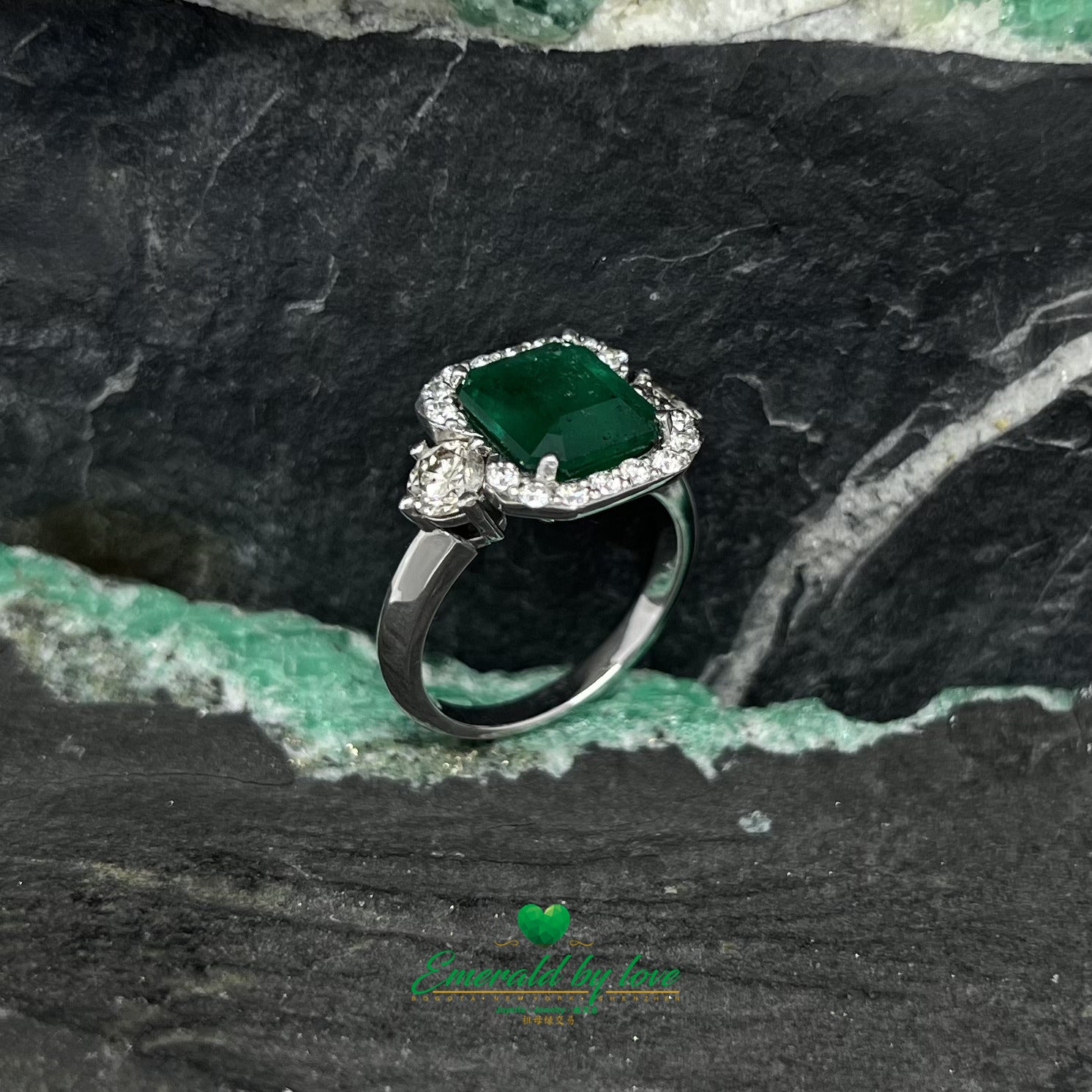 White Gold Ring with Emerald Cut Emerald Center, Flanked by Two Medium Diamonds, and Surrounded by Small Diamonds