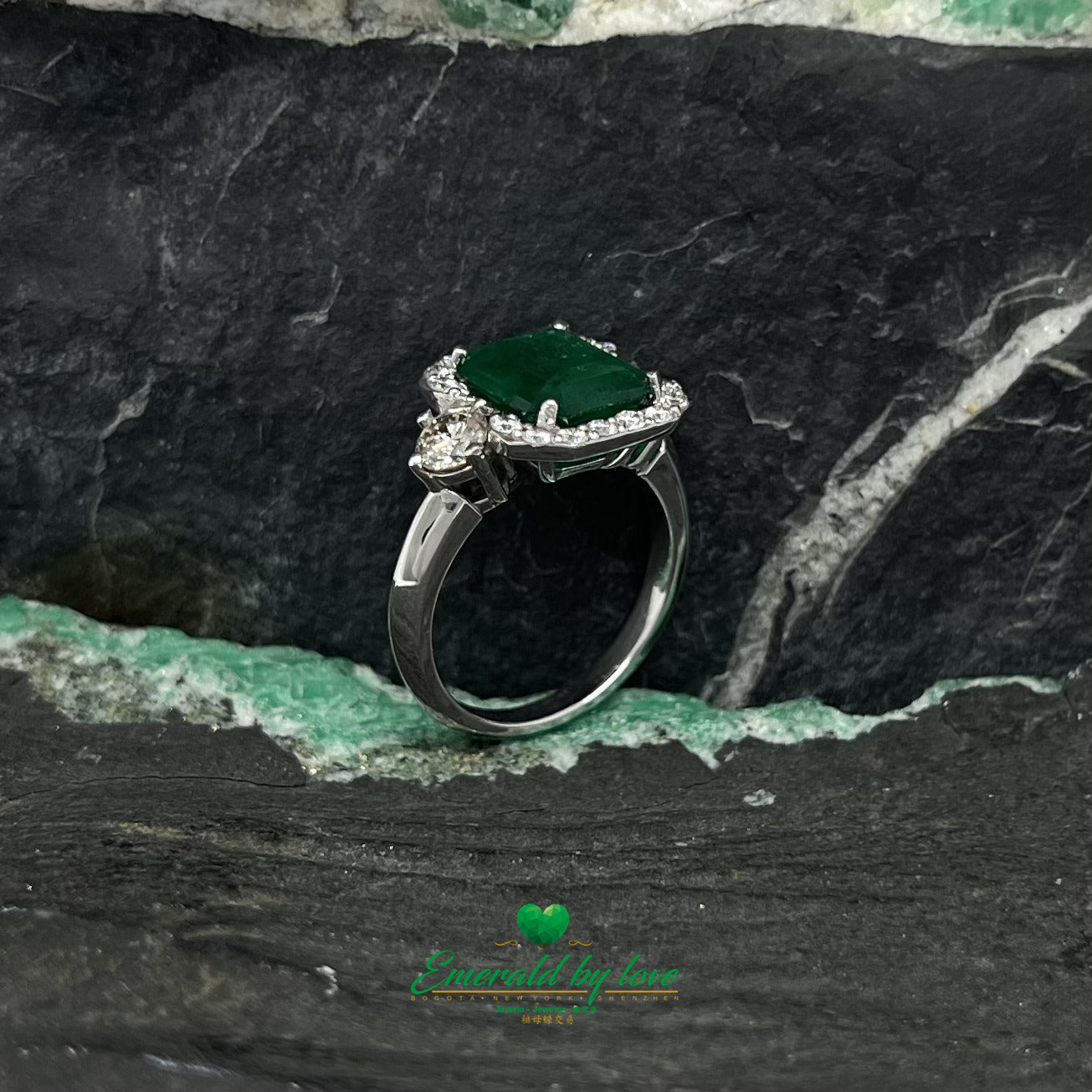 White Gold Ring with Emerald Cut Emerald Center, Flanked by Two Medium Diamonds, and Surrounded by Small Diamonds