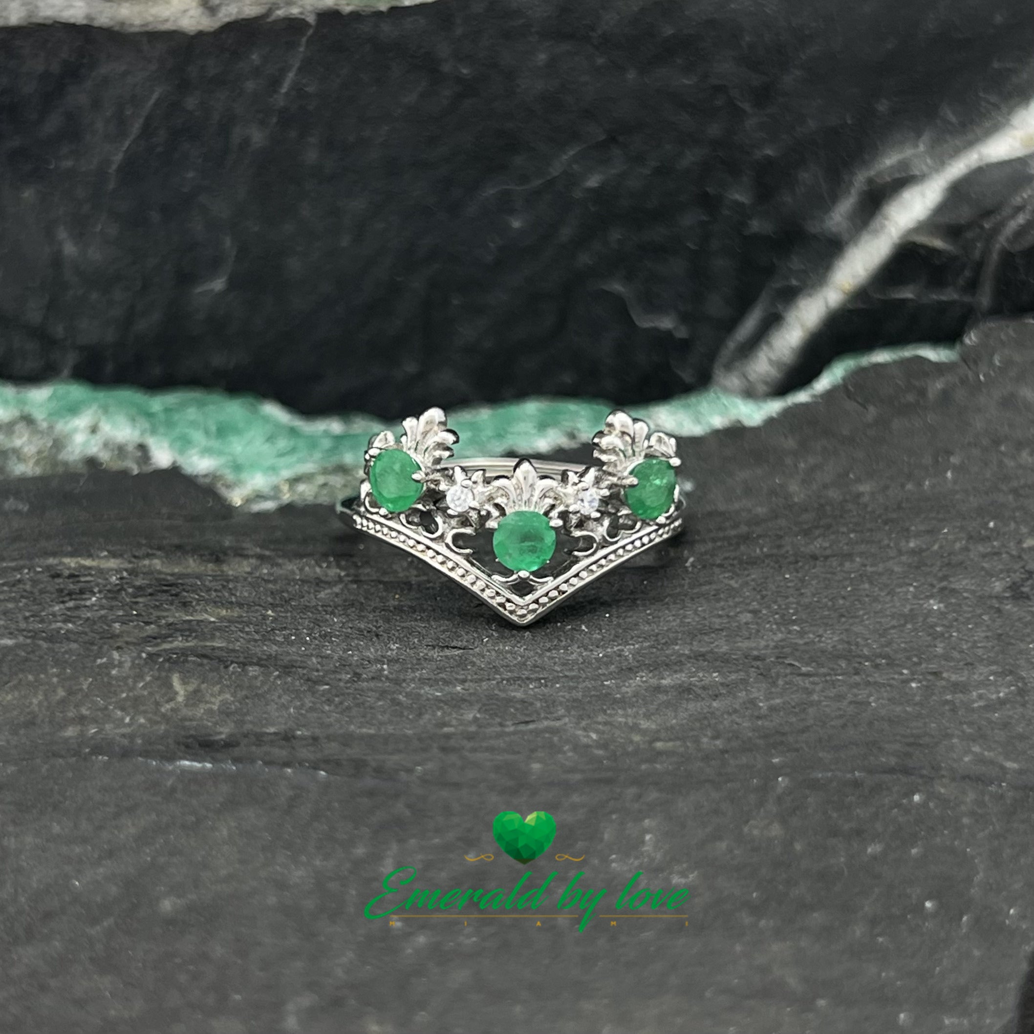 Bague de style couronne avec pointes vers le bas et émeraudes rondes entourées d'arabesques