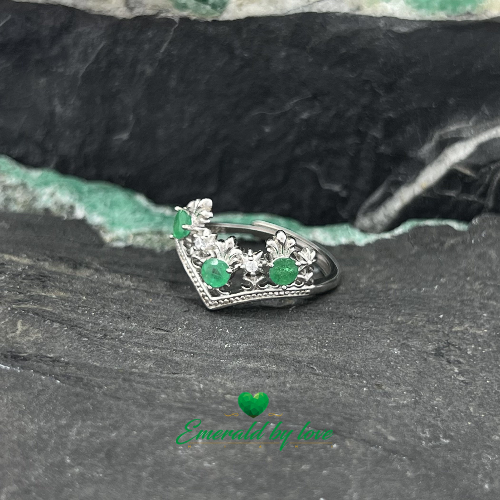 Bague de style couronne avec pointes vers le bas et émeraudes rondes entourées d'arabesques