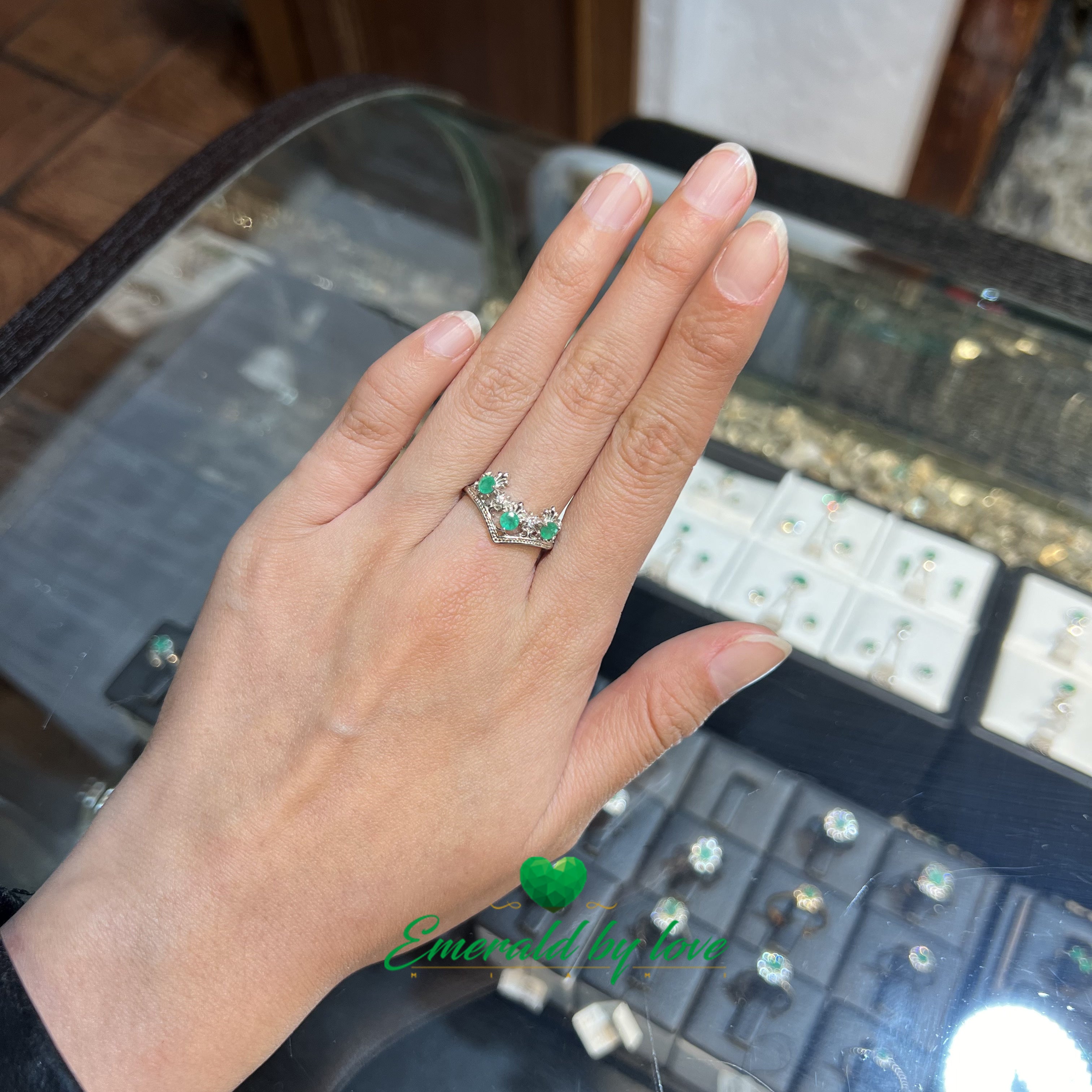 Bague de style couronne avec pointes vers le bas et émeraudes rondes entourées d'arabesques