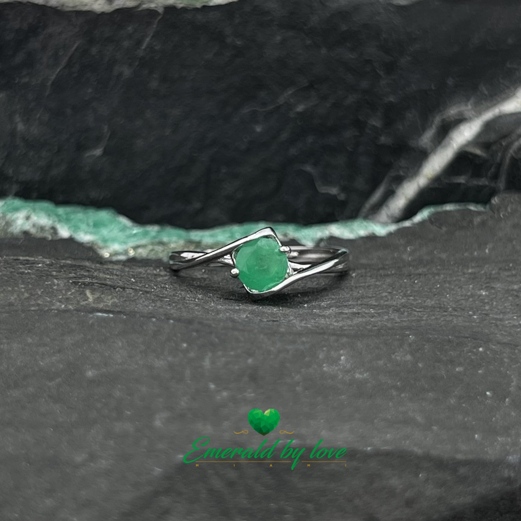 Bague solitaire avec émeraude ronde centrale et griffes décorées de cœurs