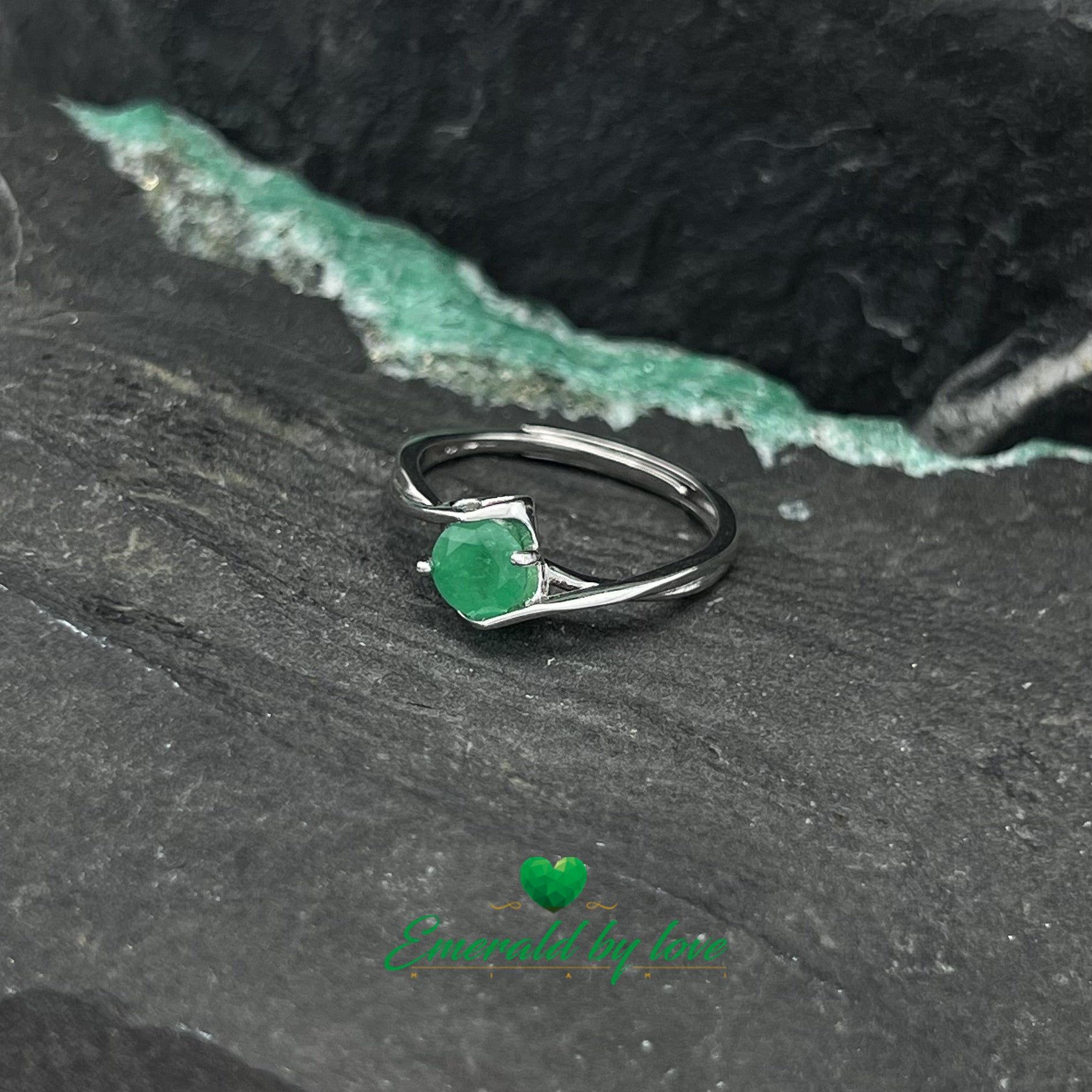 Bague solitaire avec émeraude ronde centrale et griffes décorées de cœurs