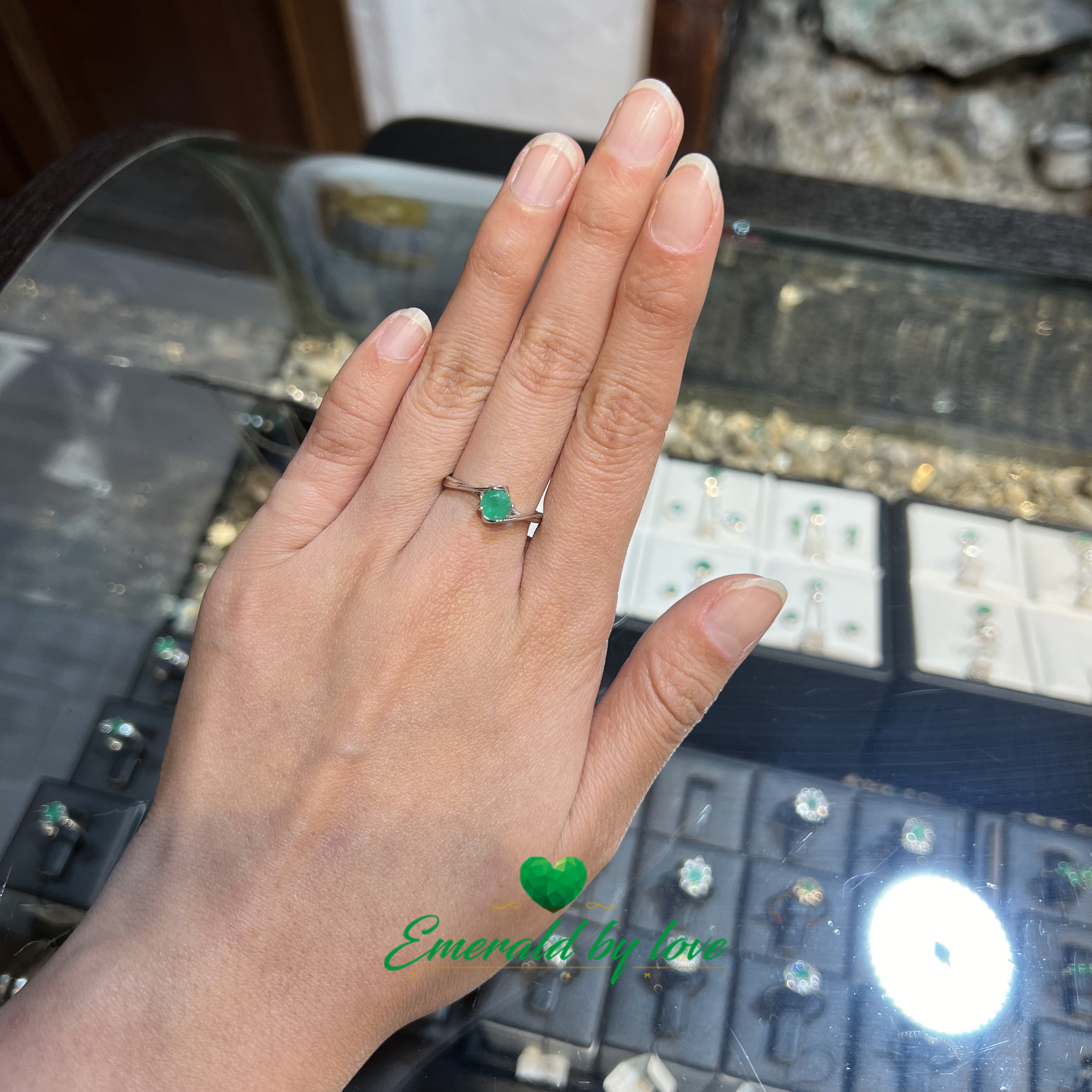 Bague solitaire avec émeraude ronde centrale et griffes décorées de cœurs