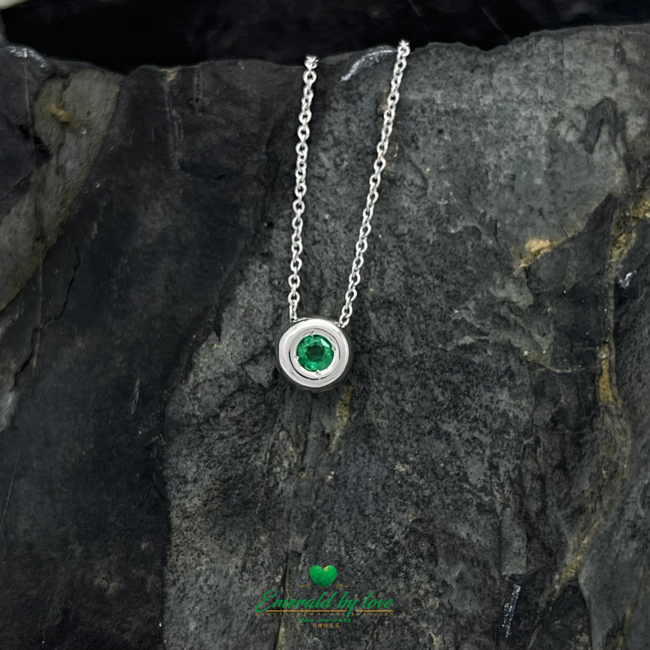 Conjunto de joyas de oro blanco con pendientes redondos y colgante con esmeralda central