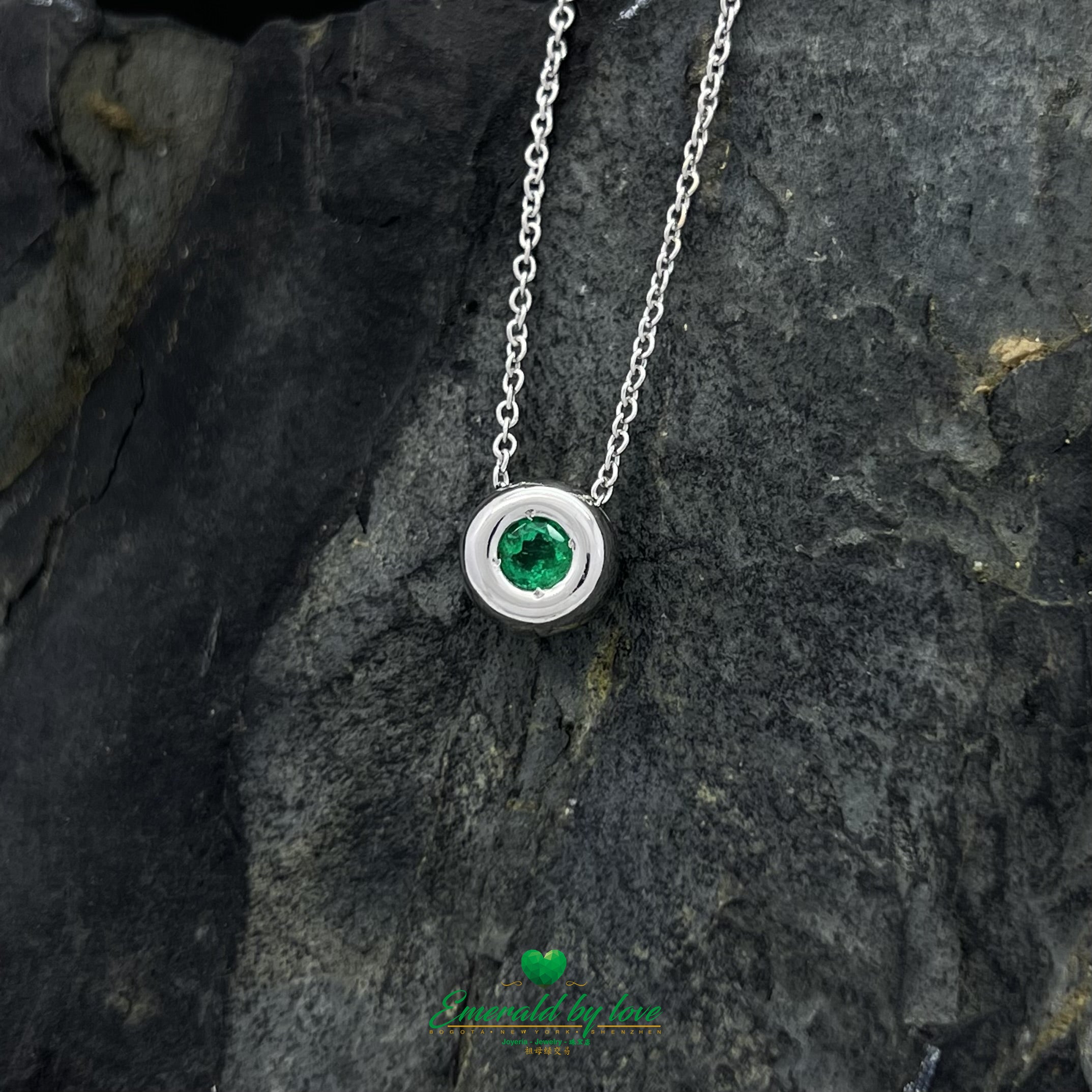 Conjunto de joyas de oro blanco con pendientes redondos y colgante con esmeralda central