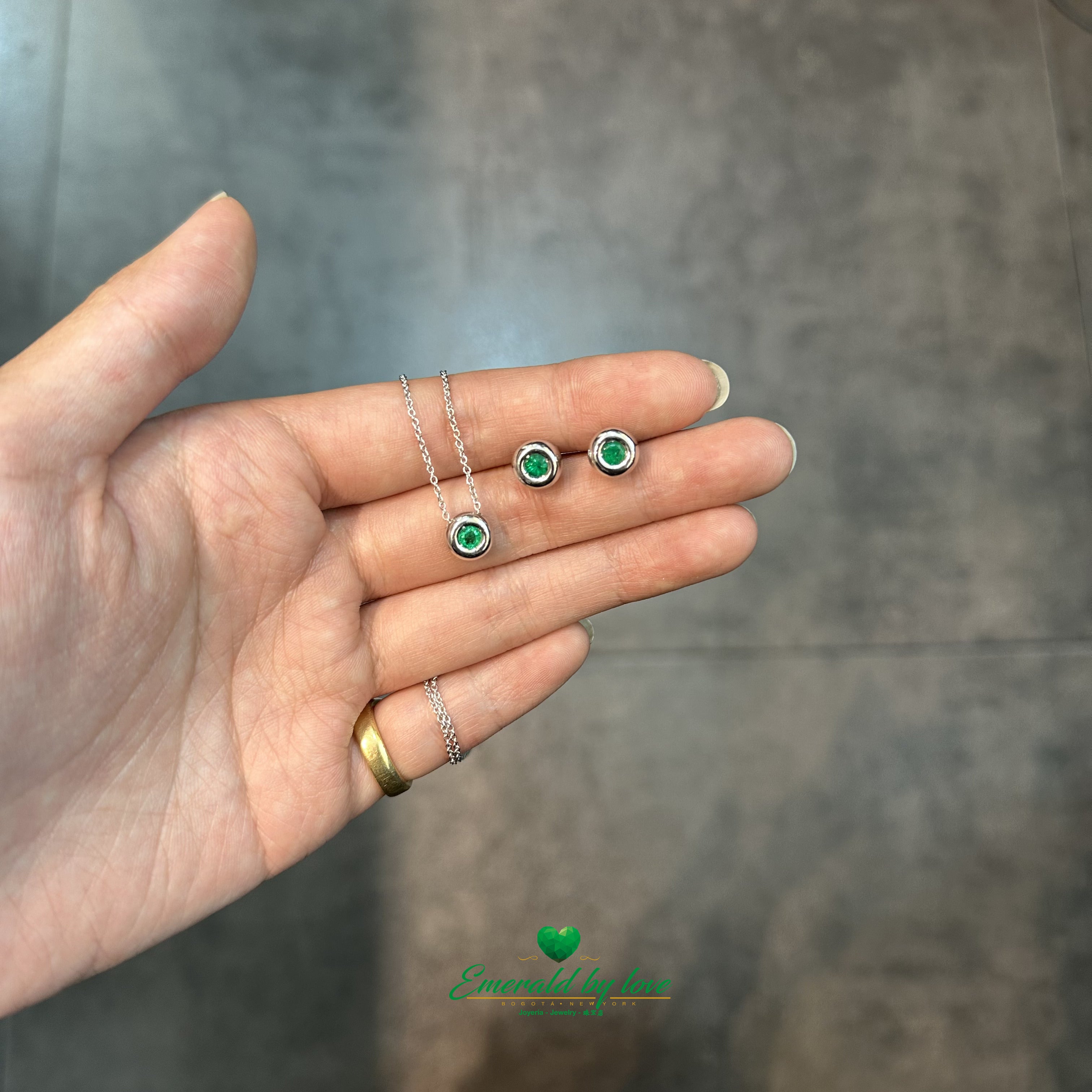 Conjunto de joyas de oro blanco con pendientes redondos y colgante con esmeralda central