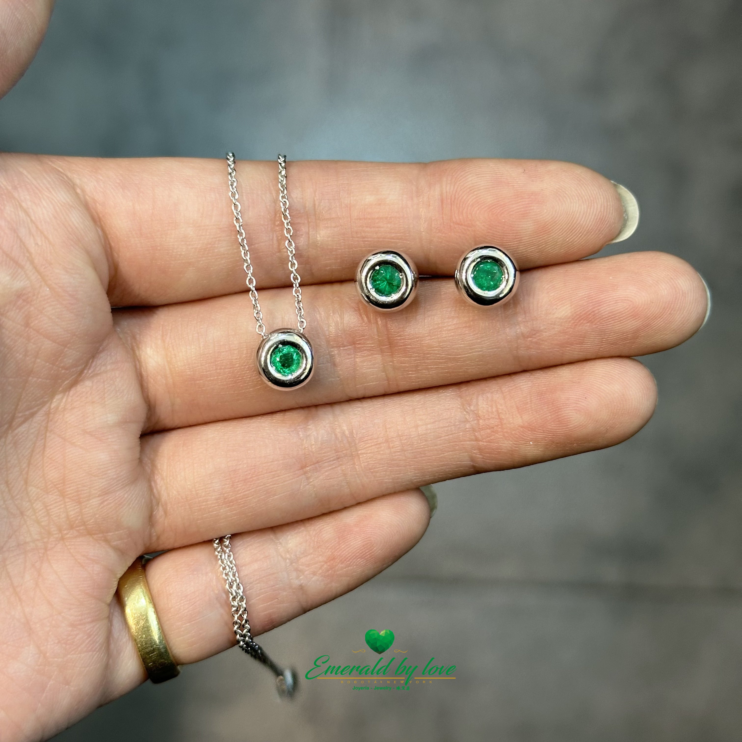 Conjunto de joyas de oro blanco con pendientes redondos y colgante con esmeralda central