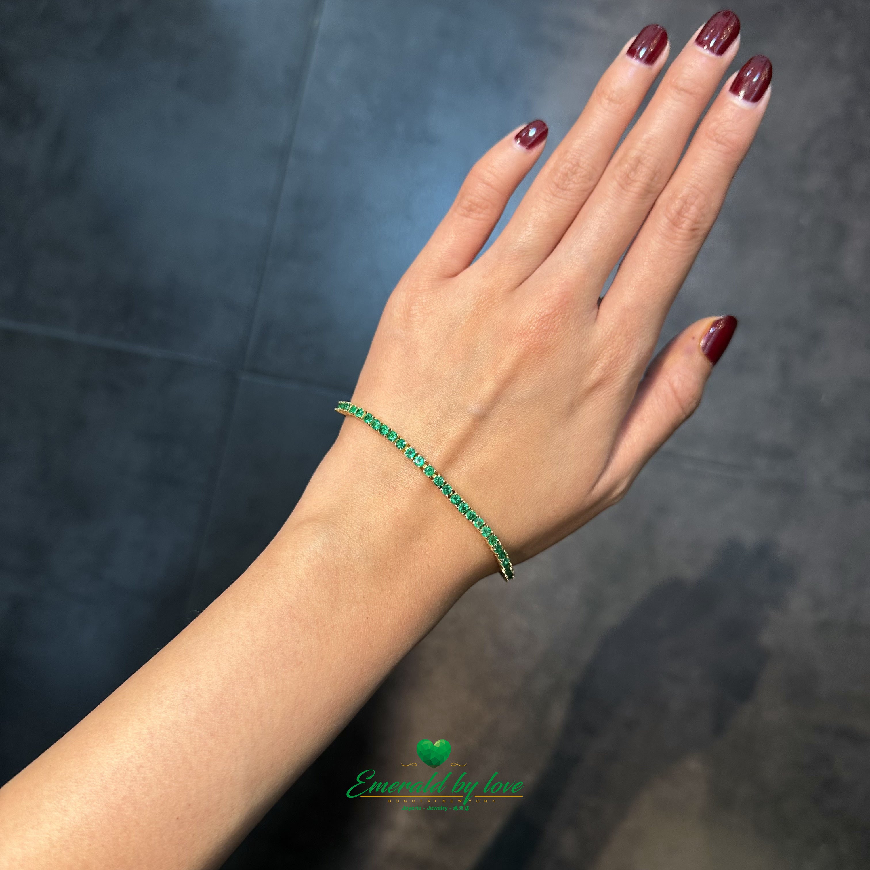 Side view of slim 18K gold bracelet with Colombian emerald stones
