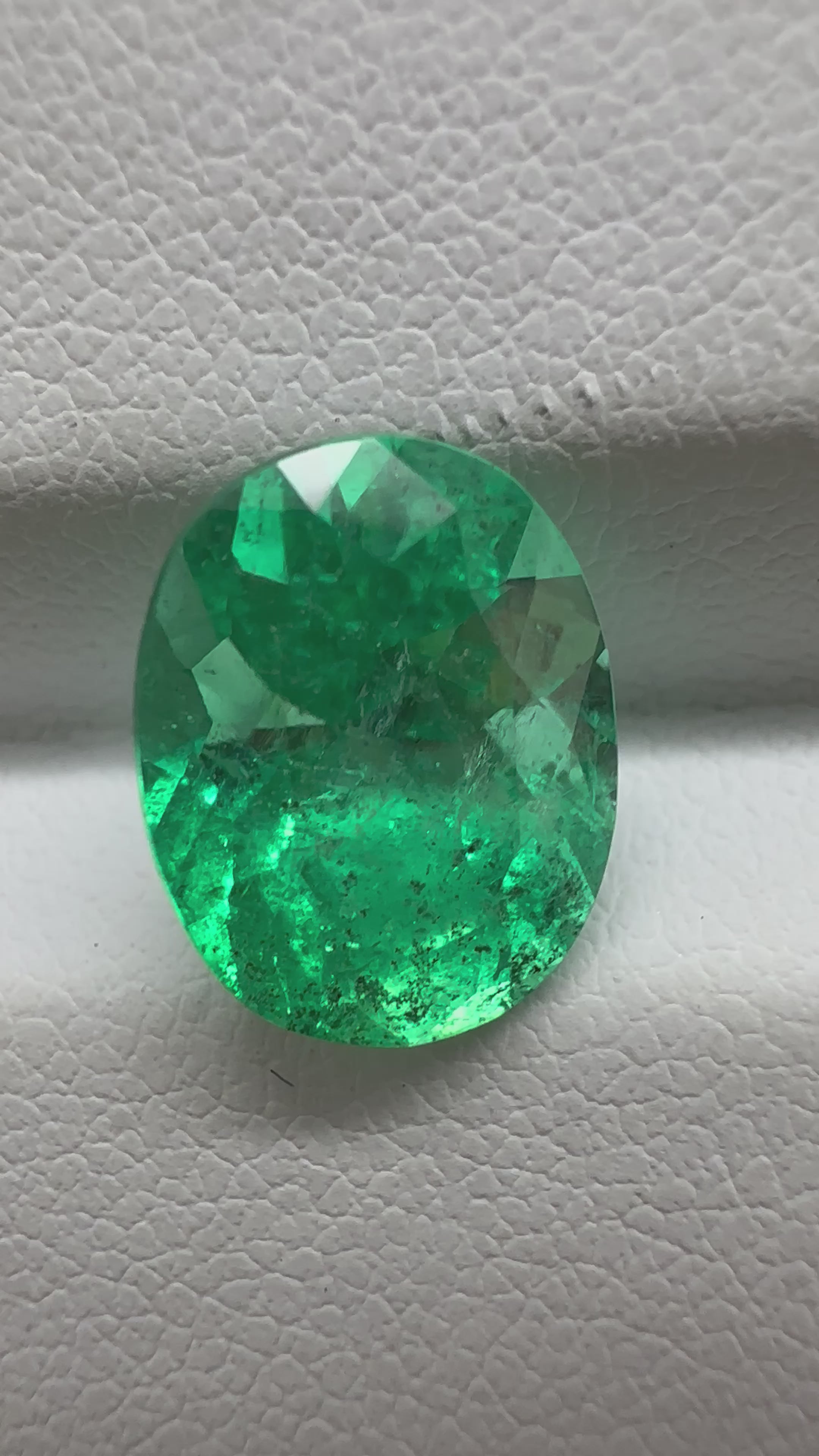 Colombian emerald in oval shape, glowing with deep green color and nature-born inclusions