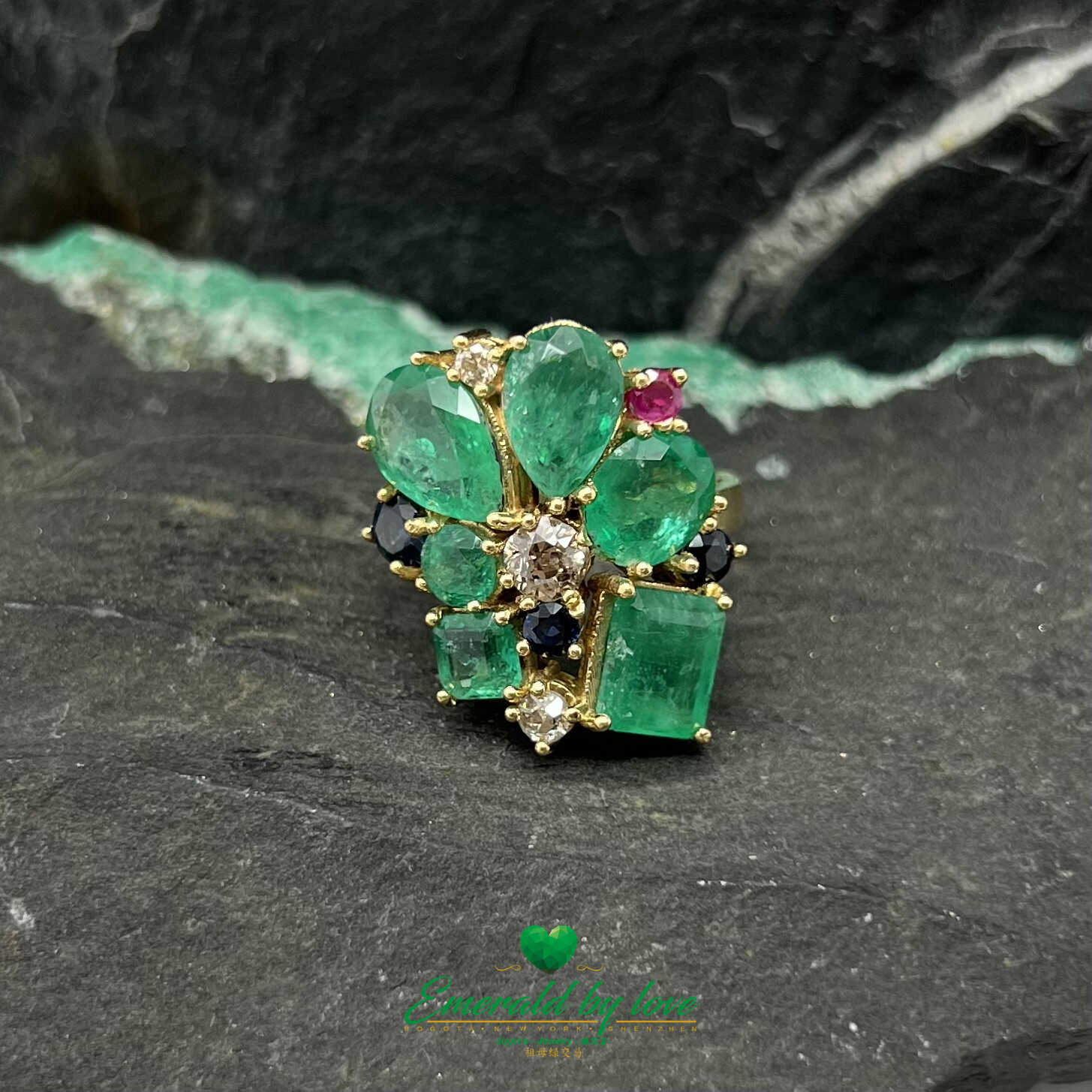 Anillo de oro amarillo adornado con esmeraldas de cristal, diamantes, zafiros y rubíes