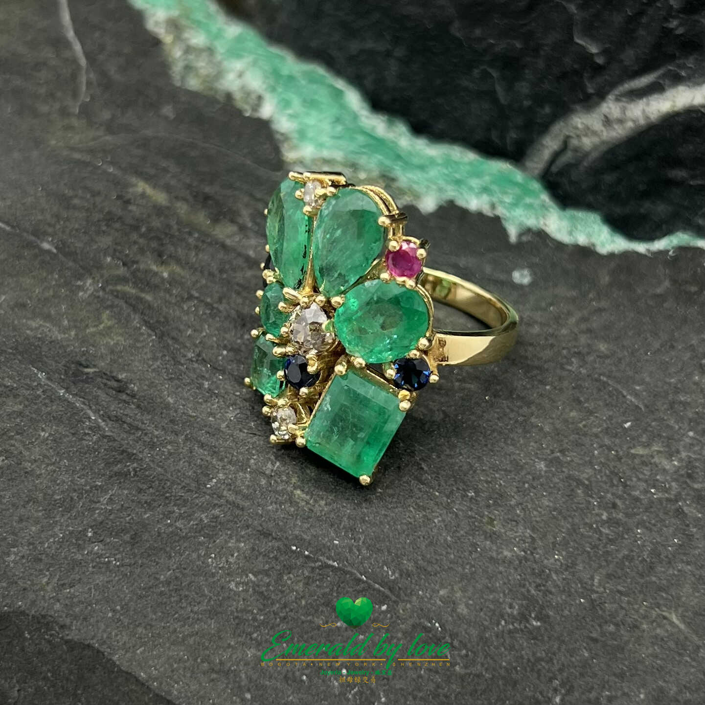 Anillo de oro amarillo adornado con esmeraldas de cristal, diamantes, zafiros y rubíes