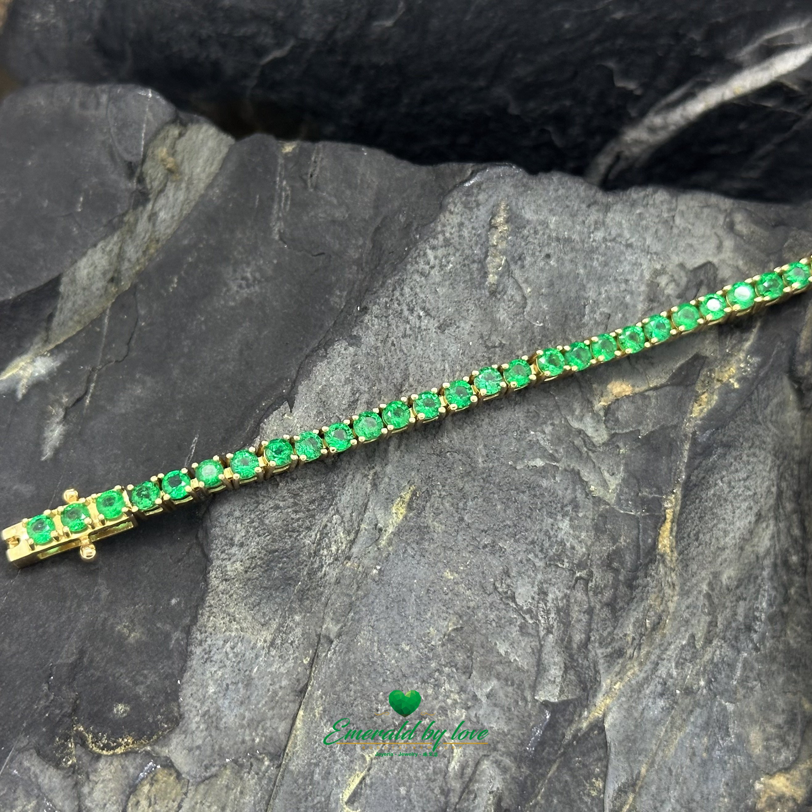 Close-up of prong-set emerald bracelet in fine yellow gold