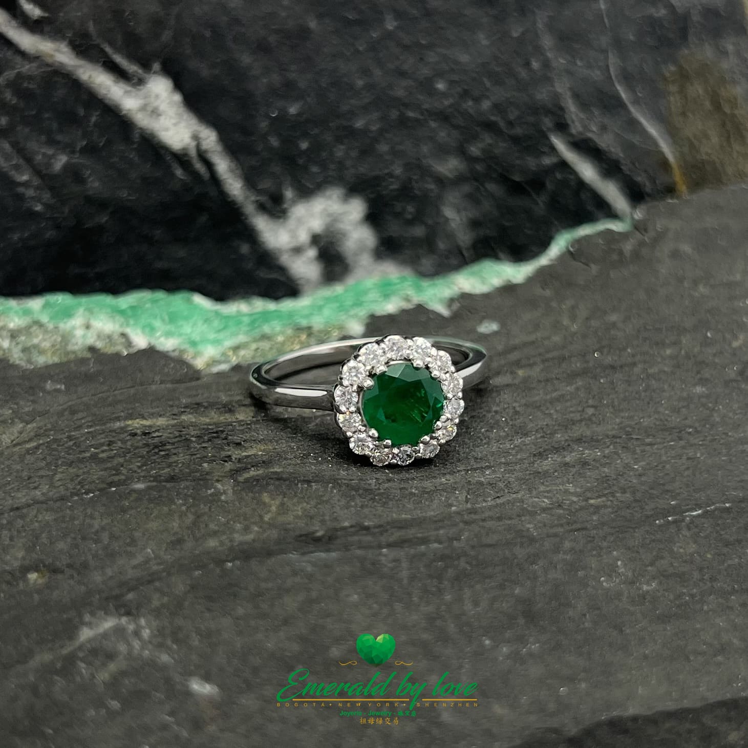 Anillo de esmeralda marquesa de oro blanco con esmeralda redonda de color verde oscuro y borde de diamantes