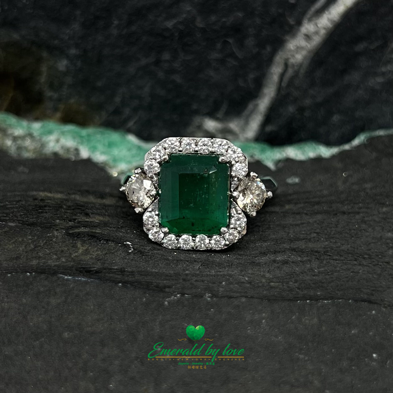 White Gold Ring with Emerald Cut Emerald Center, Flanked by Two Medium Diamonds, and Surrounded by Small Diamonds